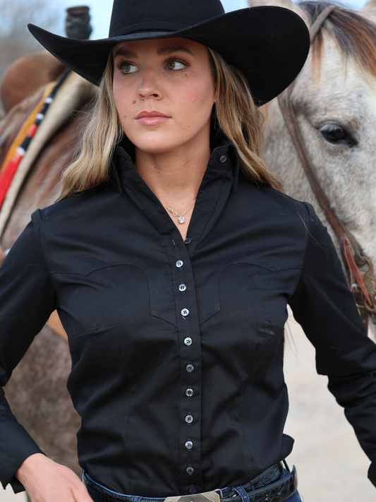 Woman wearing a black cowboy hat and shirt with a horse in the background