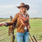 Happy Trails Wild Rag draped over shoulders and knotted at chest over white shirt and tan suede fringe jacket at ranch fence