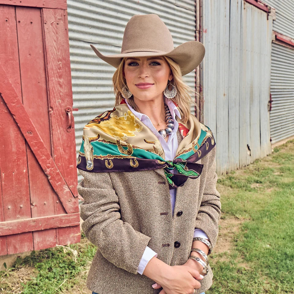Ride Em Cowboy Wild Rag tied loosely at neckline over white shirt and tan tweed blazer with silver Navajo beads and cowboy hat
