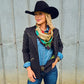 Ride Em Cowboy Wild Rag knotted at chest over denim shirt and black pinstripe blazer with black cowboy hat and concho belt