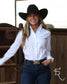 A woman wearing a black cowboy hat, a white long-sleeve button-down shirt, and dark blue jeans with a western belt stands in front of a wooden fence.